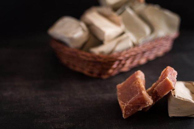 Colpo del primo piano di dolci caramelle colombiane ricoperte di foglie in un piccolo cestino su un tavolo di legno