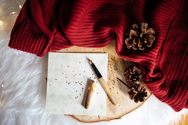 Colpo del primo piano di dossi dell'albero di Natale su tessuto rosso e una penna con adesivi a stella lucenti