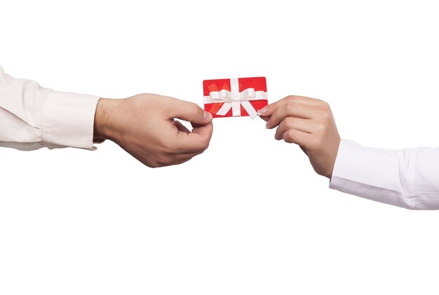 Colpo del primo piano di due persone in possesso di una carta regalo rossa su uno sfondo bianco