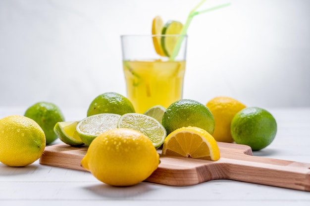 Colpo del primo piano di limoni e lime sul tagliere e sul tavolo con succo di limone