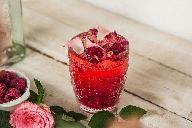 Colpo del primo piano di un bicchiere con limonata al lampone con fiori secchi