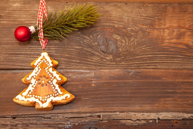 Colpo del primo piano di un biscotto a forma di albero di Natale con una piccola decorazione su uno sfondo marrone