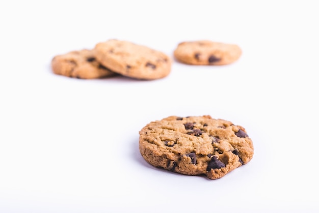 Colpo del primo piano di un biscotto di pepita di cioccolato con i biscotti in uno sfondo bianco sfocato