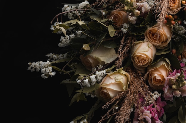 Colpo del primo piano di un lussuoso bouquet di rose arancioni e fiori bianchi su fondo nero