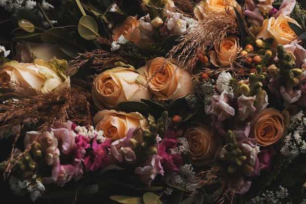 Colpo del primo piano di un lussuoso bouquet di rose arancioni e marroni su fondo nero