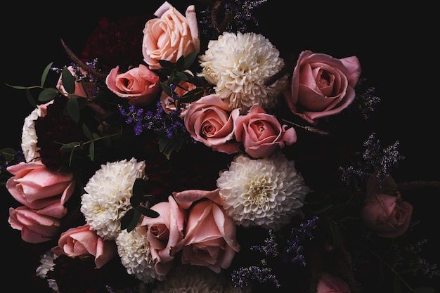 Colpo del primo piano di un lussuoso bouquet di rose rosa e dalie bianche e rosse su fondo nero