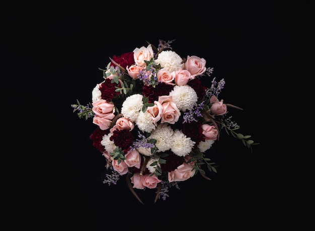Colpo del primo piano di un lussuoso bouquet di rose rosa e dalie bianche e rosse su sfondo nero