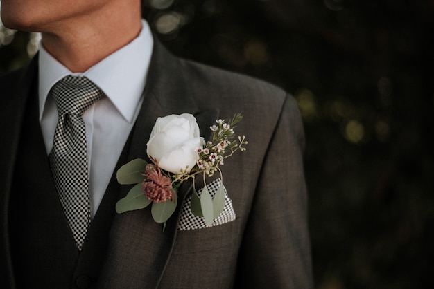 Colpo del primo piano di un maschio che indossa uno smoking con un boutonniere in tasca