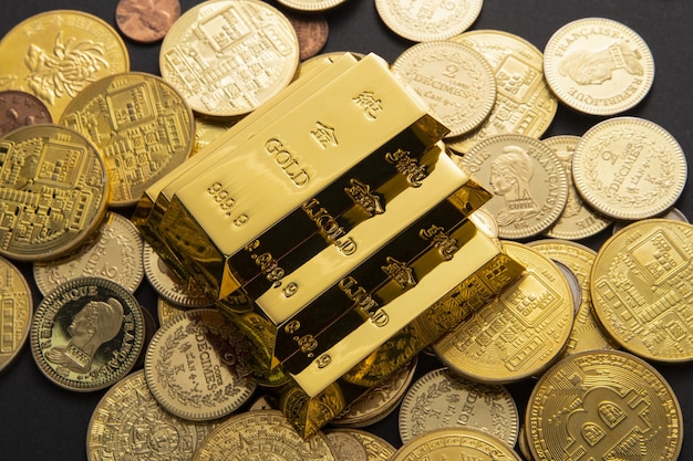 Colpo del primo piano di un mucchio di monete e lingotti d'oro lucidi