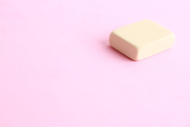 Colpo del primo piano di un pezzo di burro su uno sfondo rosa chiaro