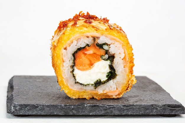 Colpo del primo piano di un rotolo di sushi su una lastra di pietra nera