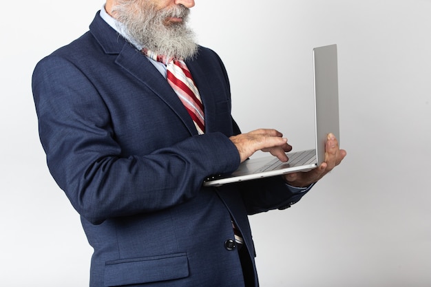 Colpo del primo piano di un uomo d'affari maschio anziano che lavora al suo computer portatile