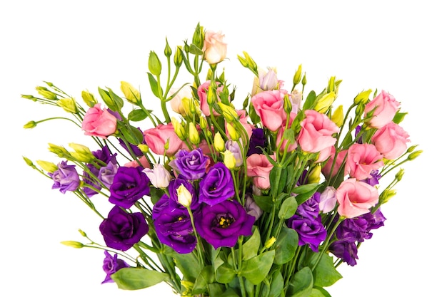 Colpo del primo piano di un vaso pieno di bellissime rose rosa e fiori viola con uno sfondo bianco