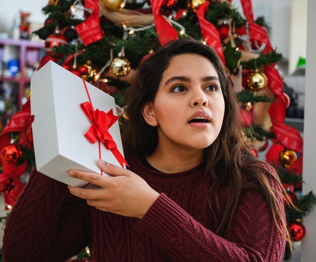 Colpo del primo piano di una bella giovane donna che tiene un regalo di Natale