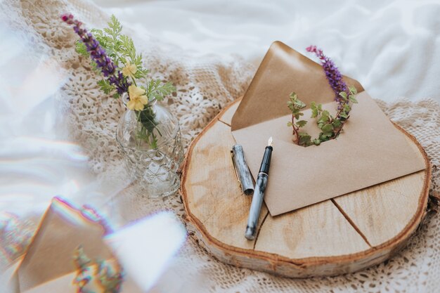 Colpo del primo piano di una busta con fiori e una penna