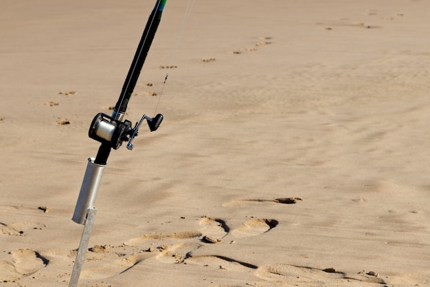 Colpo del primo piano di una canna da pesca in una superficie sabbiosa