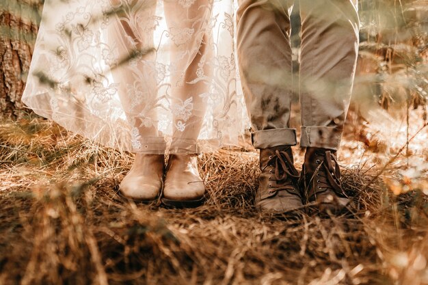 Colpo del primo piano di una coppia con vecchi stivali in un campo con erba secca durante il giorno