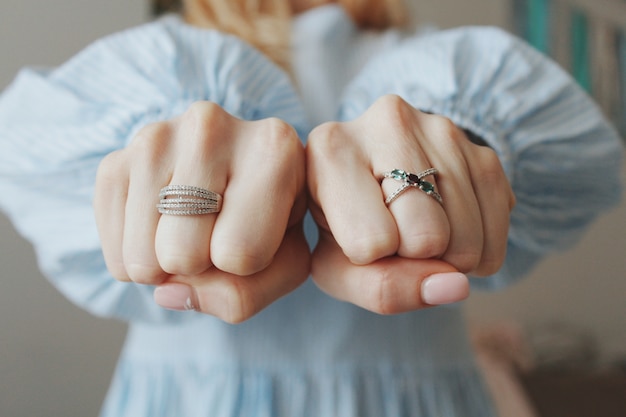 Colpo del primo piano di una donna che indossa bellissimi anelli su entrambe le mani e mostra con i pugni