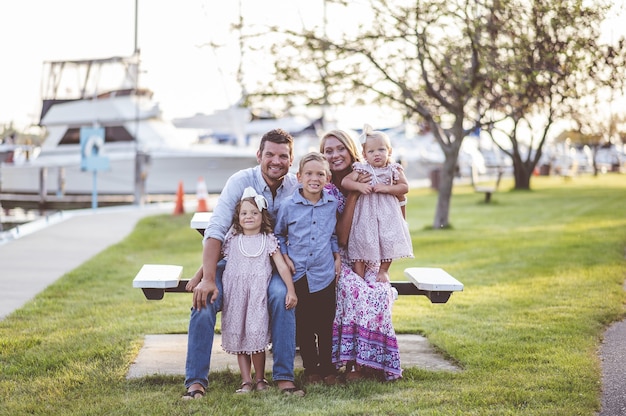 Colpo del primo piano di una famiglia felice in piedi sull'erba vicino al porto - concetto di famiglia