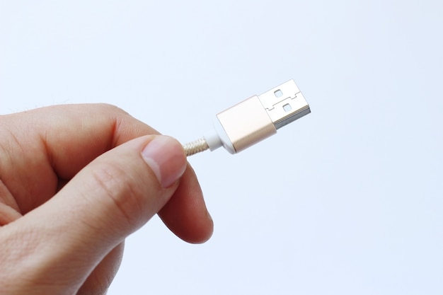 Colpo del primo piano di una persona che tiene un cavo USB con un bianco