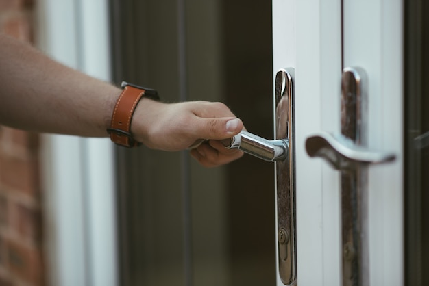 Colpo del primo piano di una persona che tiene una maniglia della porta e apre la porta