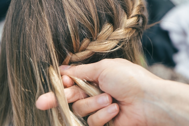 Colpo del primo piano di una ragazza che si fa le trecce