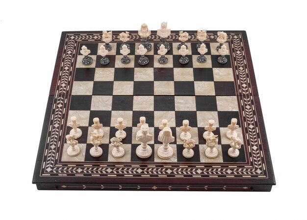 Colpo del primo piano di una scacchiera con pezzi di legno di scacchi isolati su un bianco