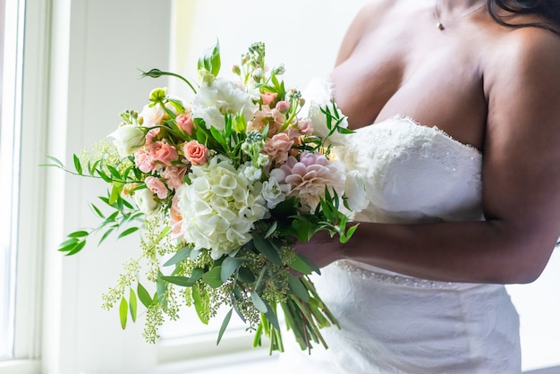 Colpo del primo piano di una sposa in un vestito bianco che tiene un mazzo di fiori