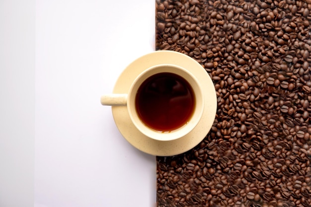 Colpo del primo piano di una tazza di caffè con chicchi di caffè su sfondo bianco