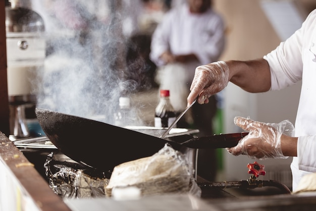 Colpo del primo piano di uno chef che cucina con uno sfondo sfocato