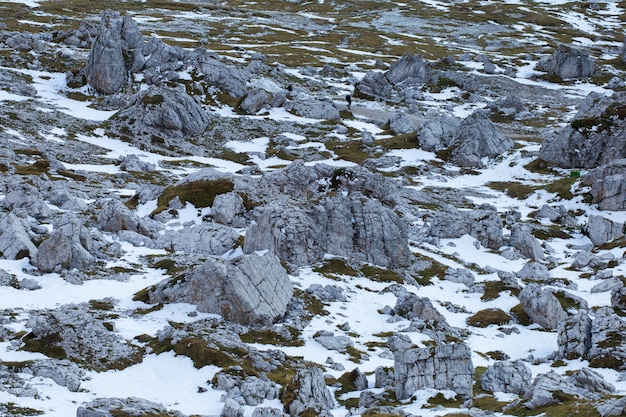 Colpo dell'angolo alto delle strutture pietrose della terra coperte di neve nelle alpi italiane