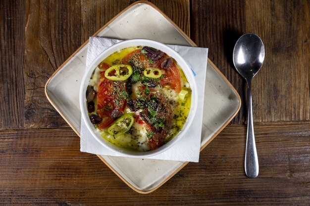 Colpo di alto angolo del piatto tradizionale con formaggio feta arrosto, peperone caldo, pomodoro e olio d'oliva