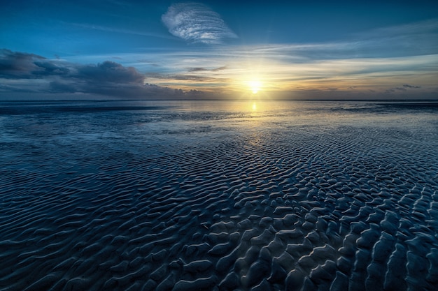 Colpo di alto angolo dell'acqua dell'oceano e del sole che splende all'orizzonte