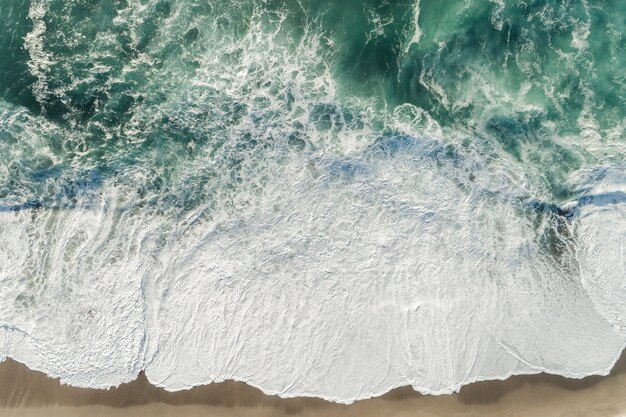 Colpo di alto angolo delle onde blu dell'oceano che spruzzano alla riva