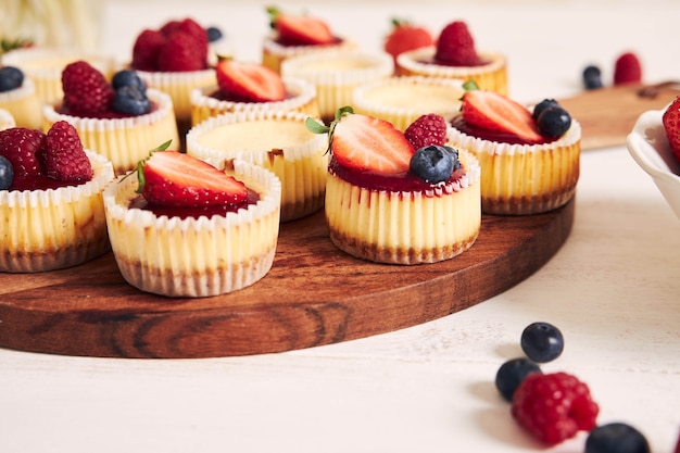 Colpo di alto angolo di cupcakes al formaggio con gelatina di frutta e frutta su un piatto di legno