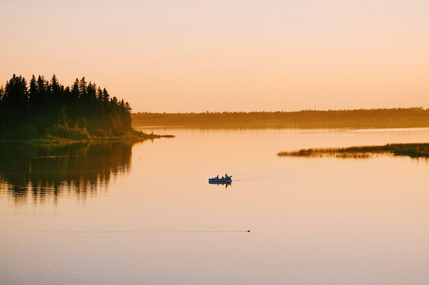Colpo di alto angolo di persone che navigano in barca nel lago durante il tramonto