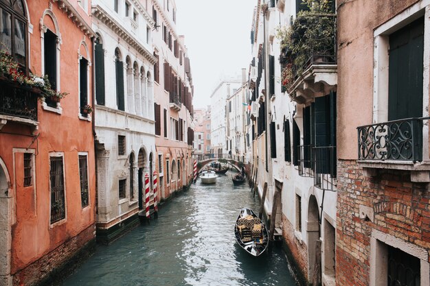 Colpo di alto angolo di un bellissimo canale a Venezia con gondole tra due edifici