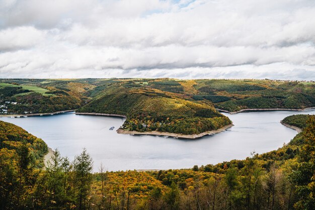 Colpo di alto angolo di un bellissimo lago circondato da colline in autunno sotto il cielo nuvoloso