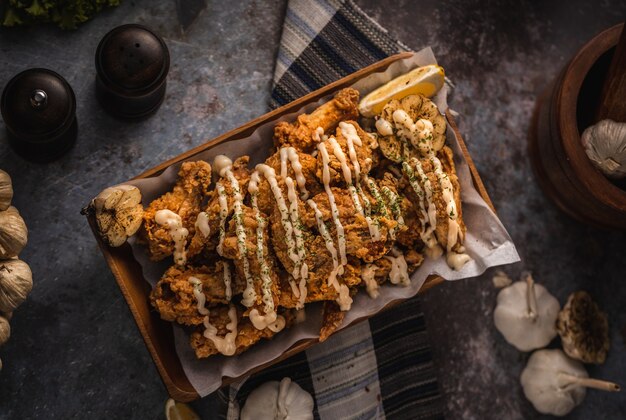 Colpo di alto angolo di un piatto di delizioso pollo fritto e un po 'di aglio su un tavolo