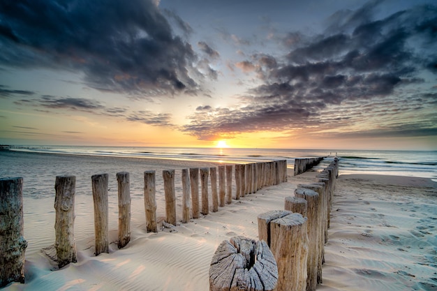 Colpo di alto angolo di un ponte di legno sulla riva che conduce al mare al tramonto