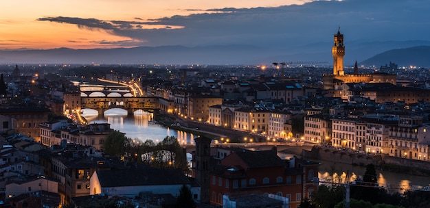 Colpo di alto angolo di un sacco di edifici con luci e un ponte di sera