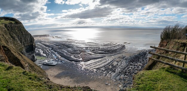 Colpo di alto angolo di una bellissima spiaggia sotto le colline e il cielo nuvoloso sullo sfondo