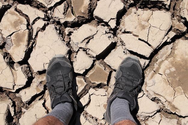 Colpo di alto angolo di una persona in piedi sul terreno fangoso essiccato e incrinato