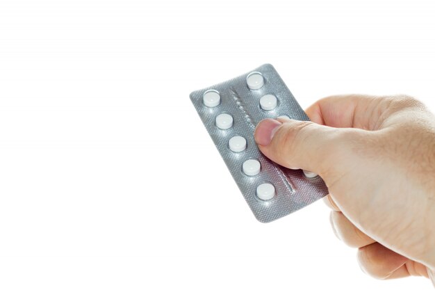 Colpo di alto angolo di una persona in possesso di un pacco di pillole bianche su uno sfondo bianco