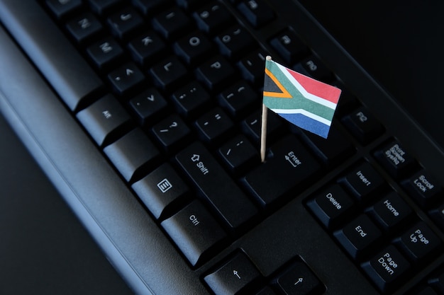 Colpo di alto angolo di una piccola bandiera del Sud Africa sulla tastiera di un computer nero