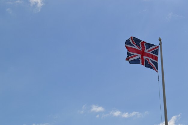 Colpo di angolo basso della bandiera della Gran Bretagna su un palo sotto il cielo nuvoloso