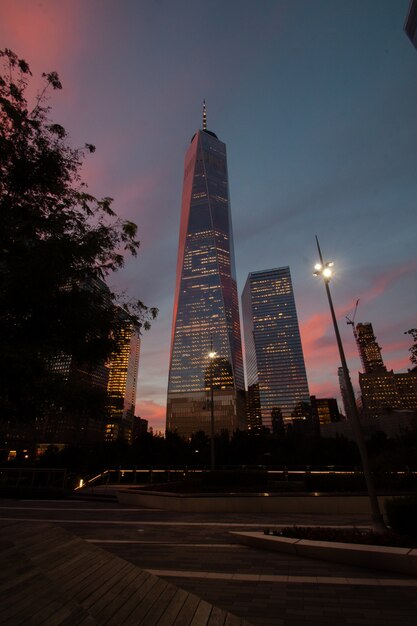Colpo di angolo basso verticale di grattacieli illuminati sotto il cielo al tramonto
