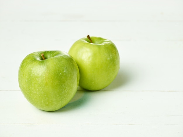Colpo di due mele verdi fresche con foglia verde su un tavolo.