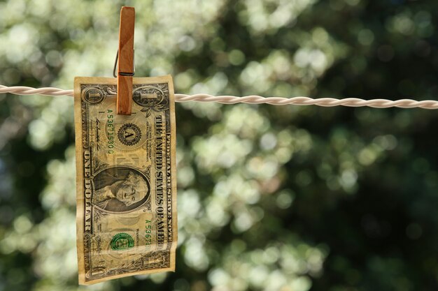 Colpo di messa a fuoco selettiva di una banconota da un dollaro appesa a un filo con una molletta
