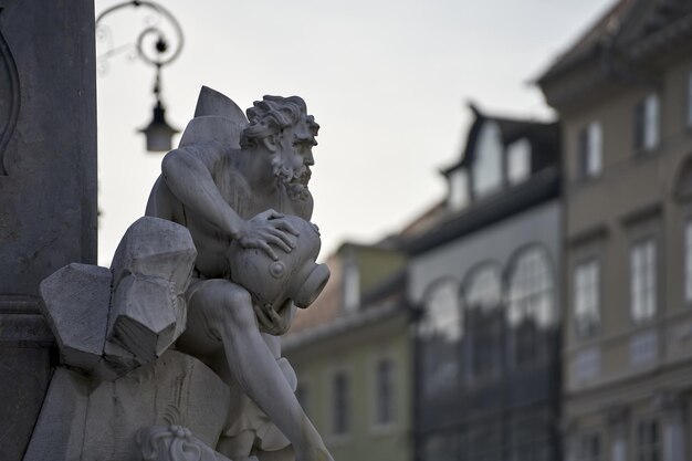 Colpo di messa a fuoco selettiva di una statua di un uomo che tiene una ciotola davanti a un edificio